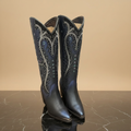 Botas vaqueras azul noche sobre mármol oscuro, vista frontal