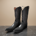 Botas vaqueras negras sobre mármol oscuro, vista frontal
